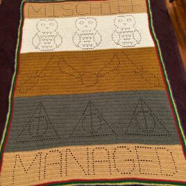 crocheted blanket with owls, quidditch, and the deathly hallows symbols wit the words Mischief Managed